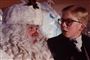 en lille dreng med briller kigger forfærdet på en julemand