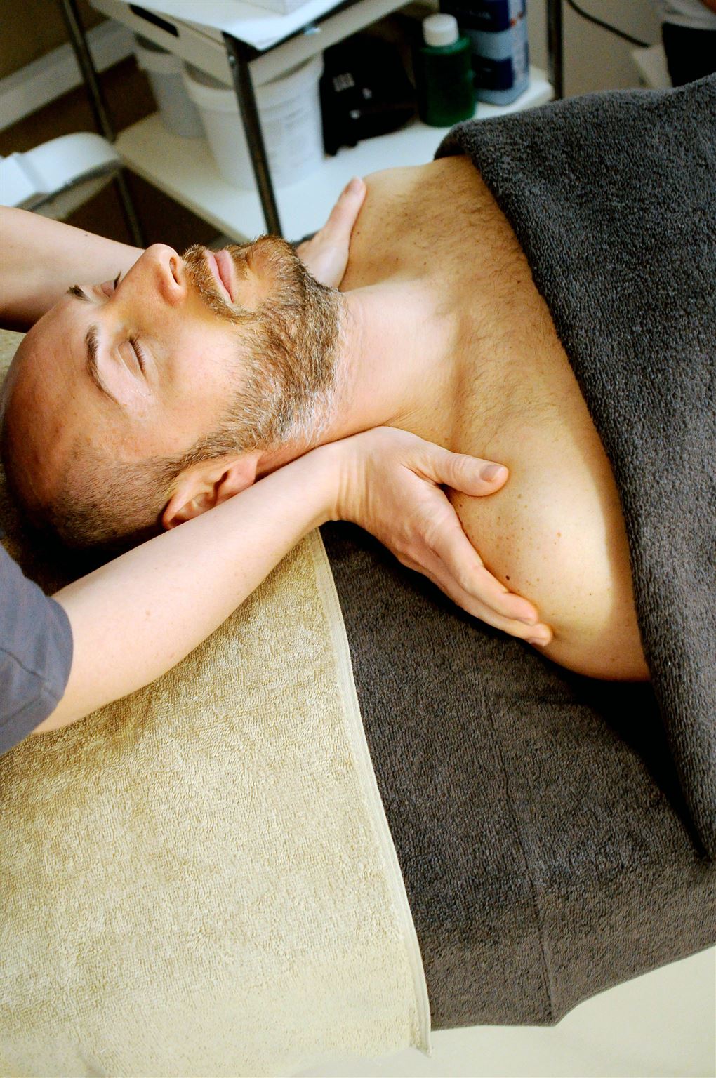En mand på en briks får massage ved skuldrene