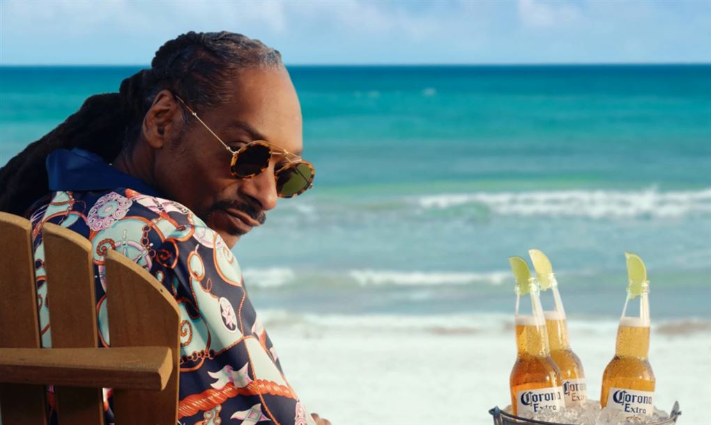 Snoop Dogg i en strandstol med nogle Corona-øl ved siden af