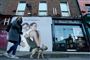 En kvinde lufter sin hund i Dublin foran en plakat med ordlyden: Vi vil kramme igen.