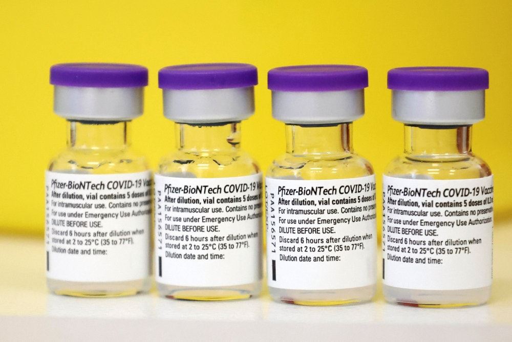 fire glas med coronavaccine på bord med gul baggrund