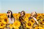 tre smilende piger på blomstermark 
