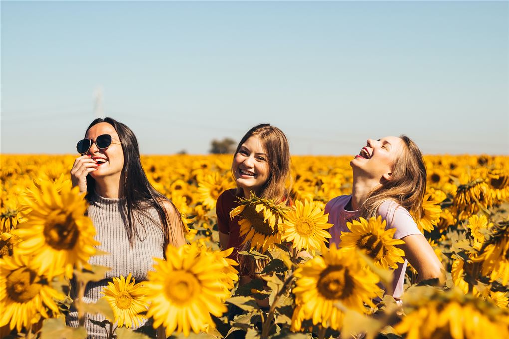 tre smilende piger på blomstermark 