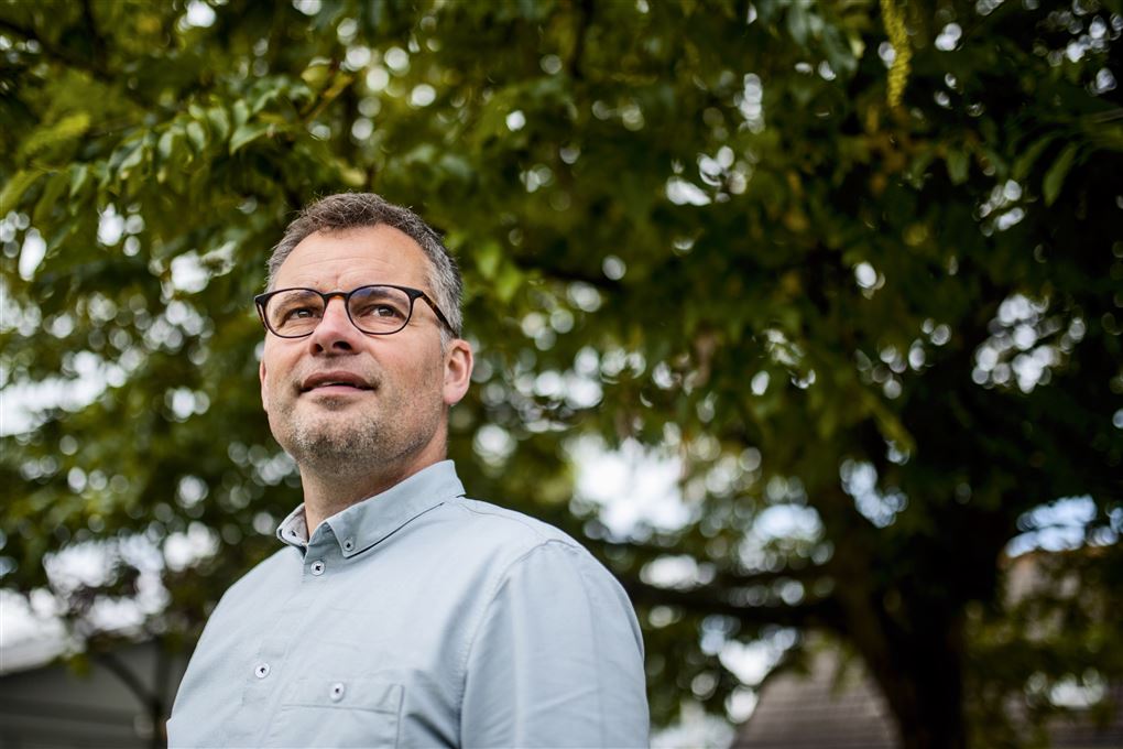 Billede af en mand i skjorte med et træ i baggrunden