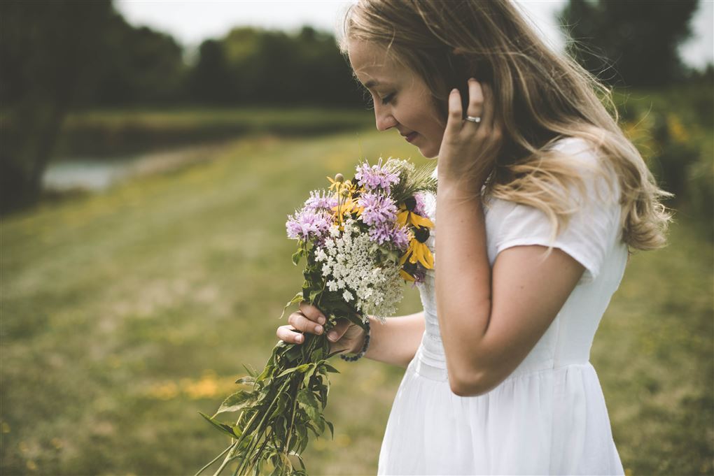 kvinder står på eng og dufter til blomster
