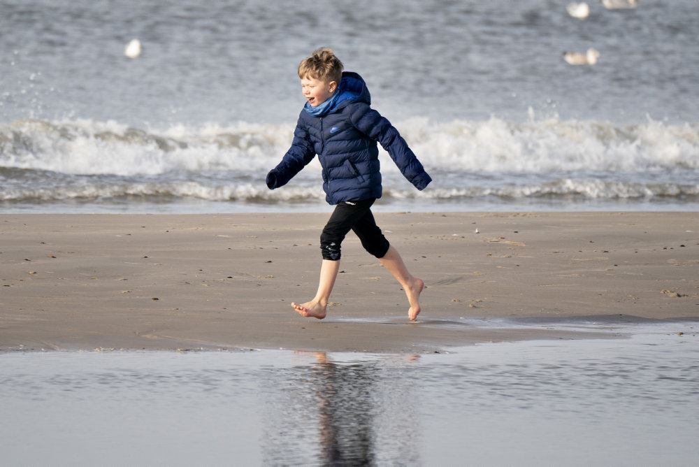 dreng løber på strand i bare tæer