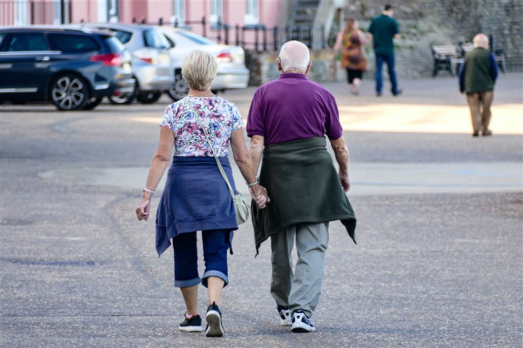 Ældre ægtepar går tur med hinanden i hånden.