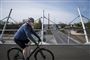 En cyklist kører over en bro. Han har cykelhjelm på. 