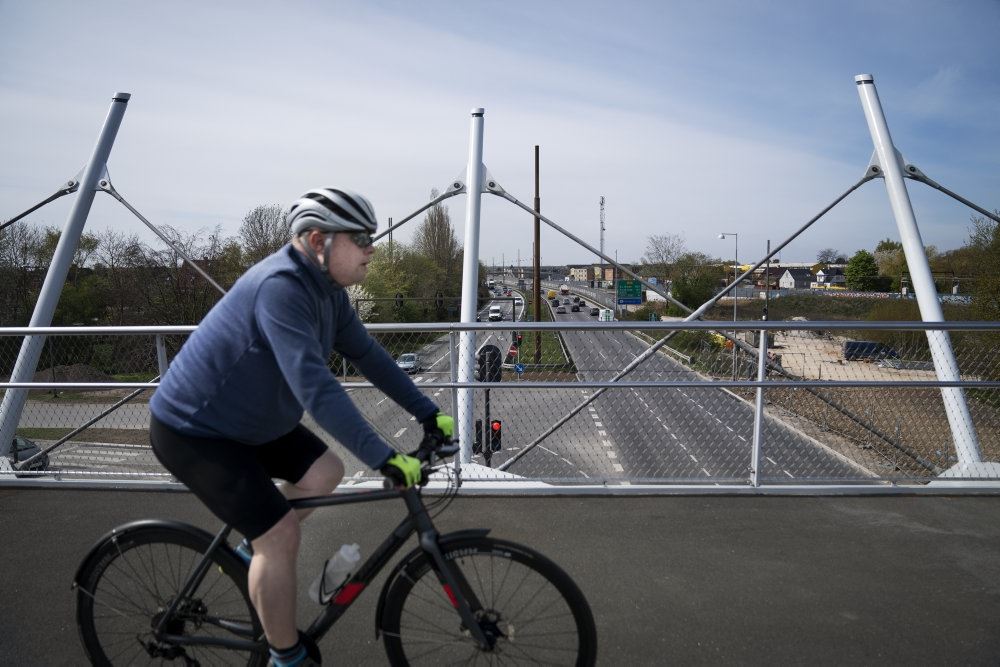 En cyklist kører over en bro. Han har cykelhjelm på. 