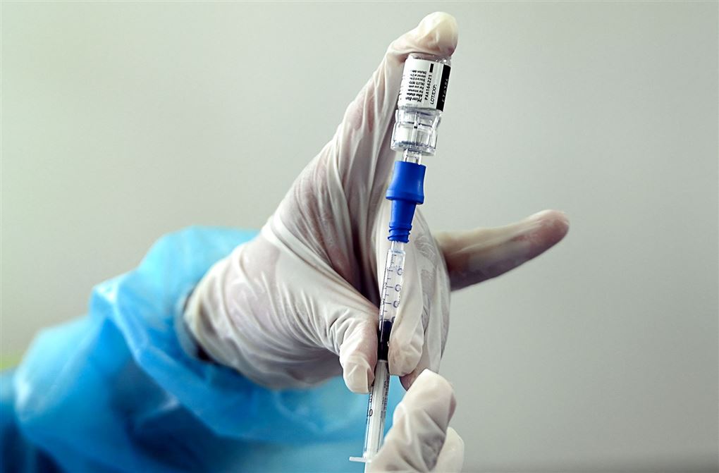 person holder kanyle og vaccineglas i hånden