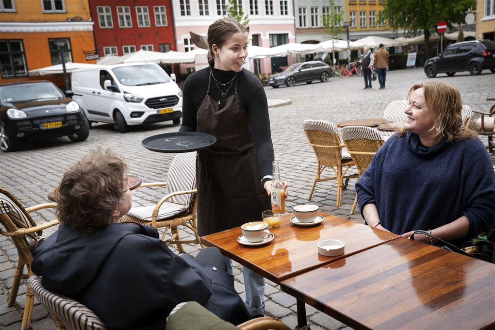 En tjener serverer kaffe til to kvinder