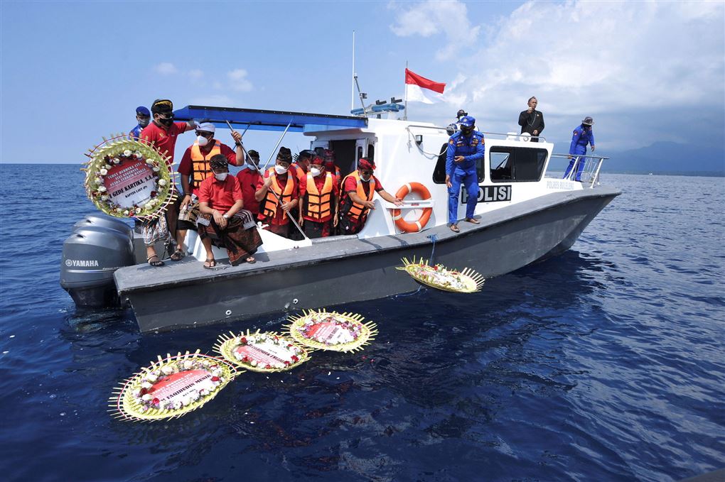 En båd med folk om bord smider blomster i vandet