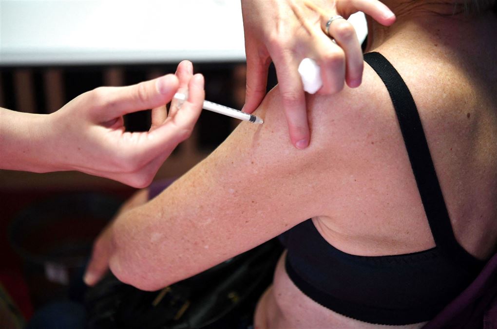 En kvinde får en dosis vaccine i den ene overarm.