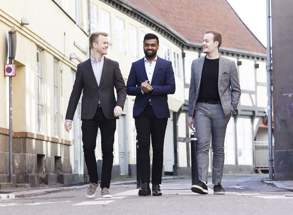 tre mænd går ned ad gaden i jakkesæt