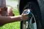 person vasker hjulkapsel på bil 