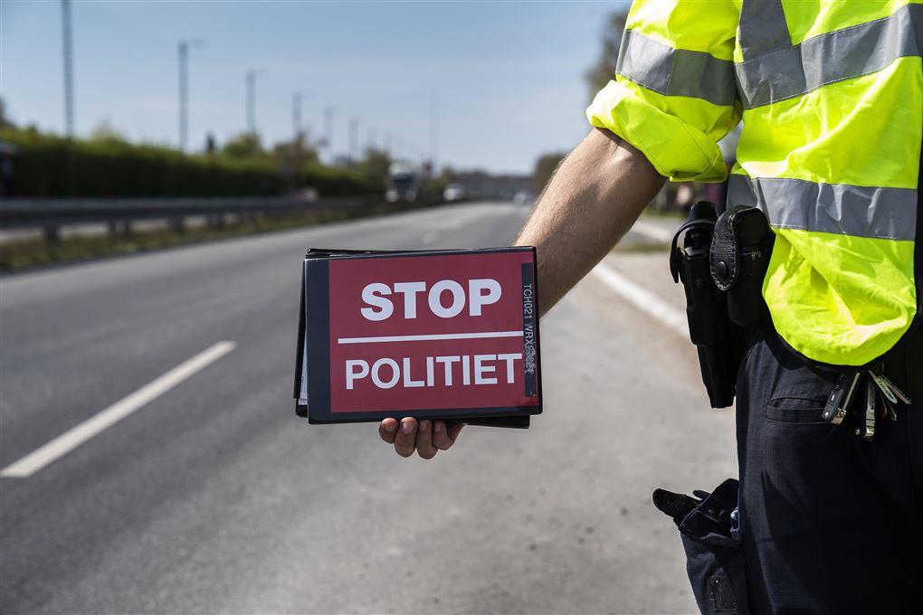 politimand holder rødt stopskilt 