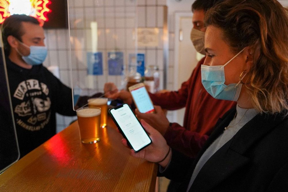 Folk i en bar med mundbind og smartphones åbne