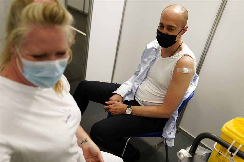 Magnus Heunicke med den ene arm ude af trøjen og et plaster på skulderen efter vaccinationen