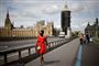 En mørk kvinde i rød kjole går på en bro med Big Ben i baggrunden
