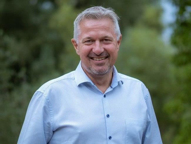 En smilende mand i blå skjorte