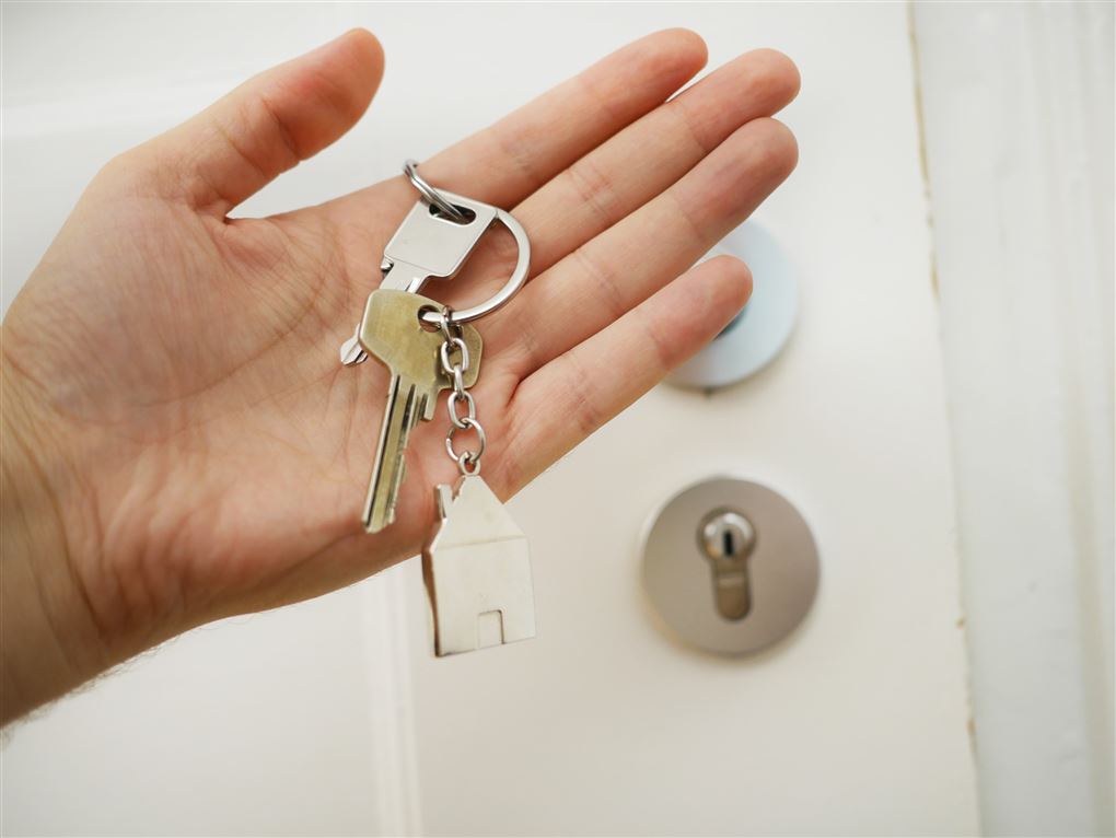 En hånd med to nøgler i foran en hoveddør