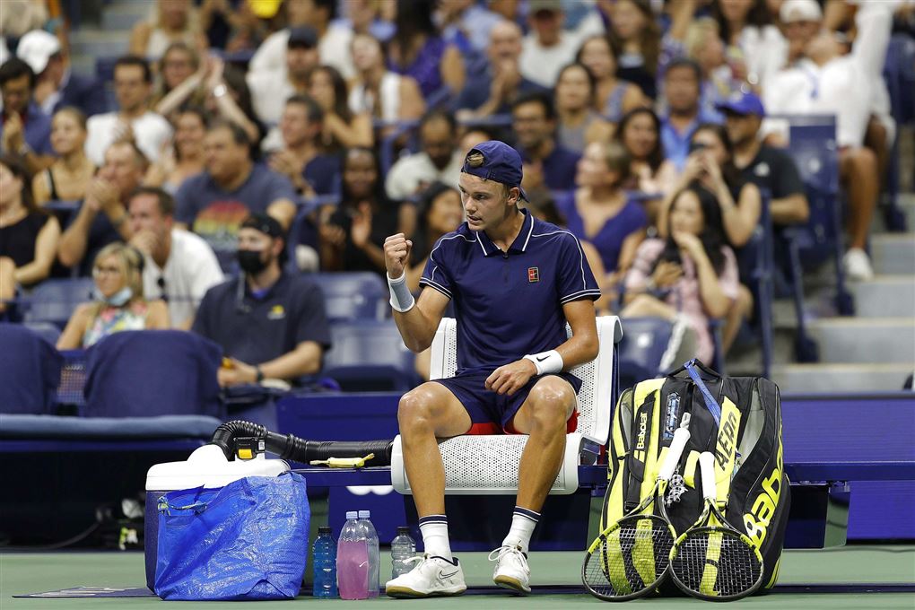 tennisspilelr sidder på stol under kamp med blå ikea-pose ved sin side 