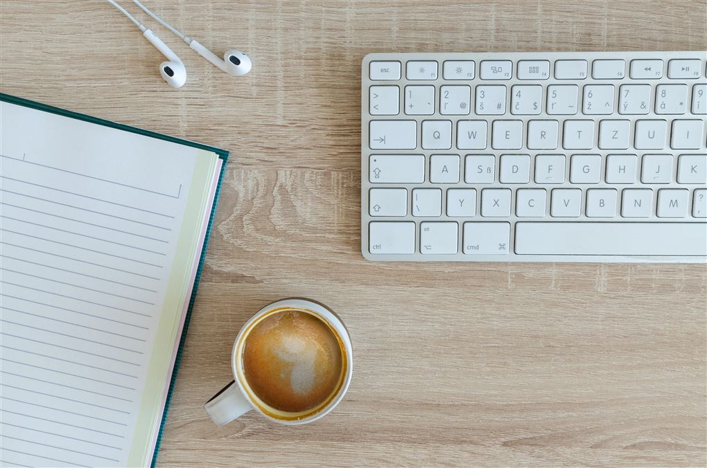 Et tastatur og en kop kaffe på et bord
