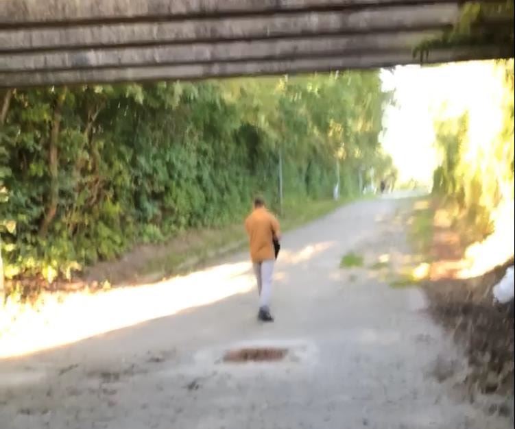 Et sløret billede af en mand i karrygul jakke set bagfra et stykke nede af en vej. 