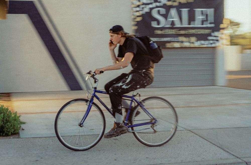 mand kører på cykel og taler i mobiltelefon samtidig