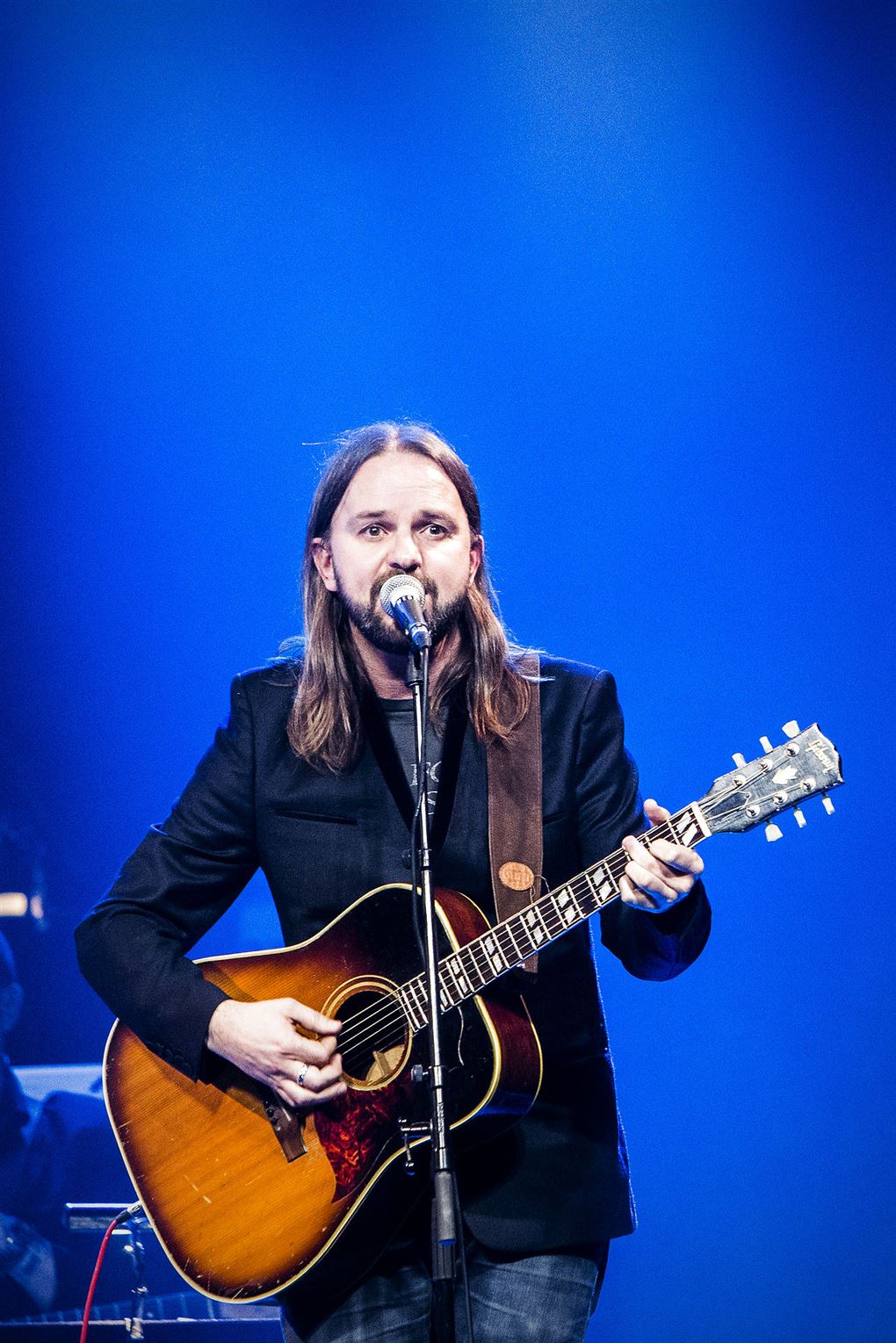 Tim Christensen på scenen med sin guitar og blå baggrund.