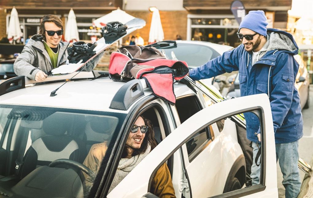 Unge mænd pakker skiudstyr i en bil