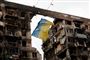 ukrainsk flag foran en ødelagt bygning