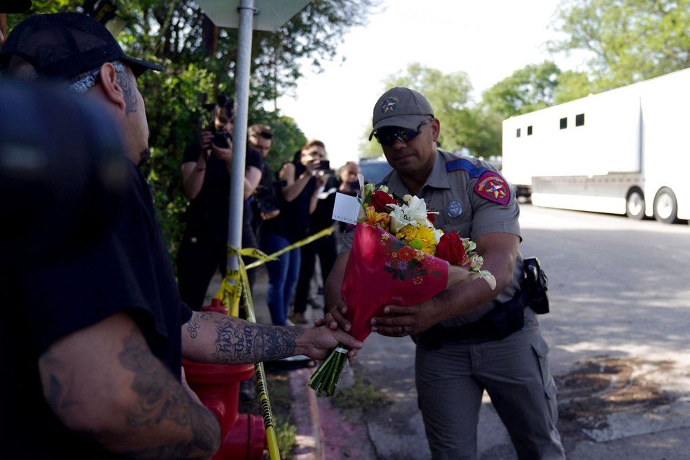 En politimand tager imod blomster fra en lokal indbygger for at lægge dem på et mindested uden for skolen Robb Elementary School i Uvalde i Texas.