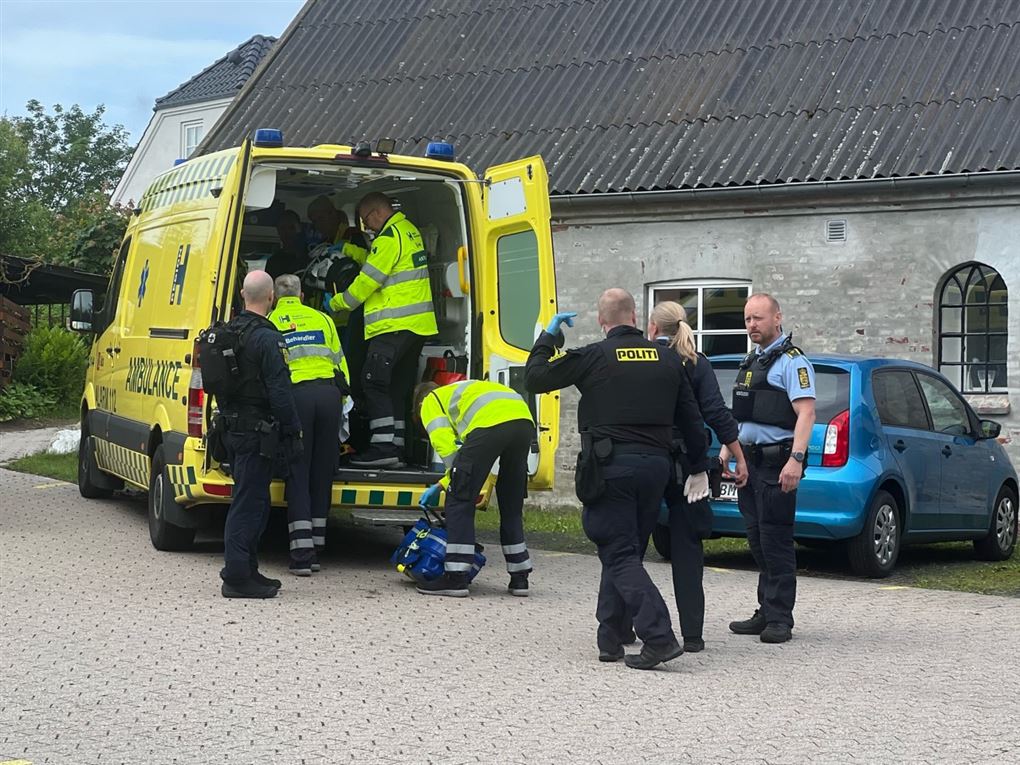 Ambulancefolk og politibetjente omkring en ambulance