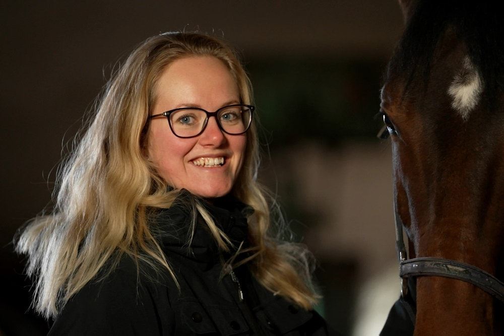 En smilende pige med briller og en hest