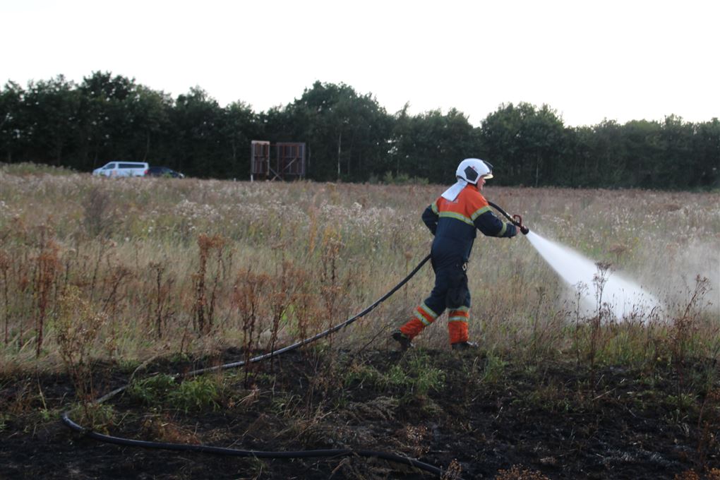 En brandmand sprøjter vand på en mark 