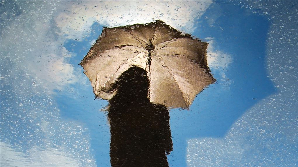 En kvinde med en paraply og en blå himmel.