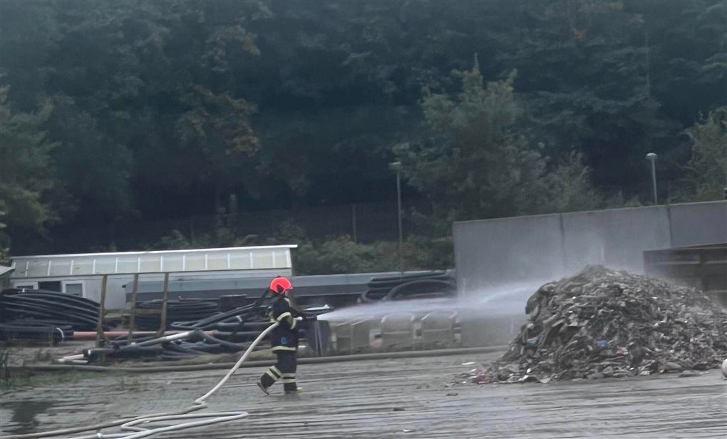 EN brandmand sprøjter med vand på en stak roer eller noget der ligner