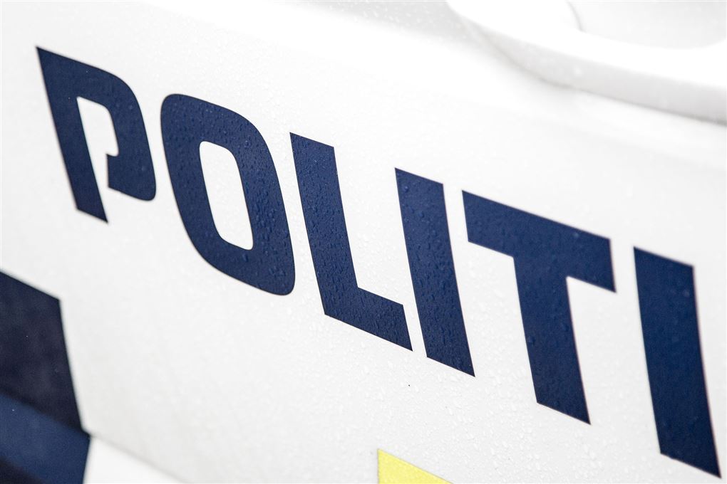 En politibil set fra siden. Den er hvid med blå skrift.