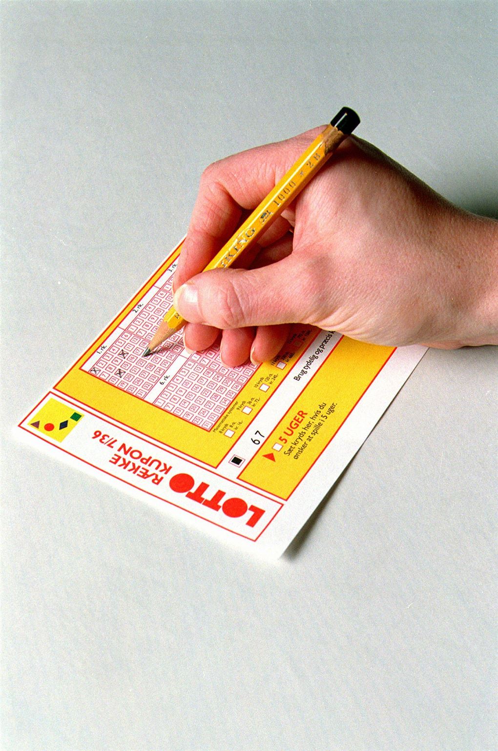 hånd med blyant udfylder lottokupon