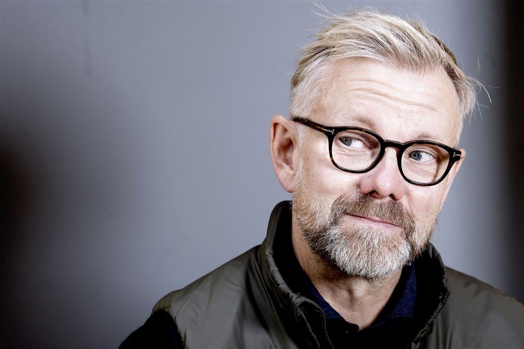 Portrætbillede af Casper Christensen med gråt hår og sorte briller