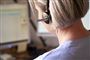 En kvinde med et headset på og en computer foran sig