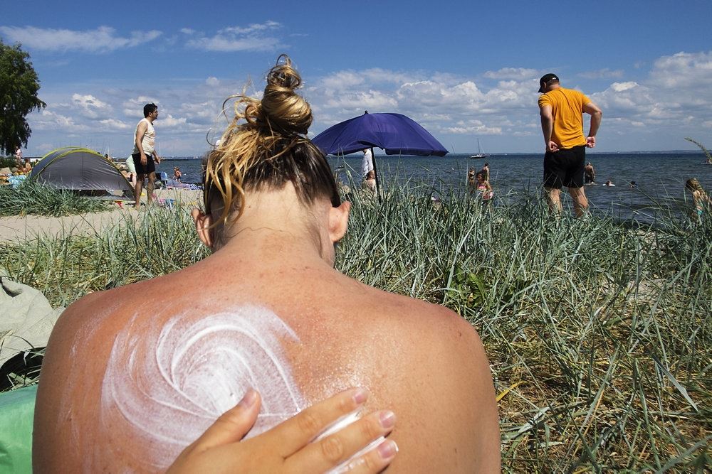 En person bliver smurt ind i solcreme på ryggen