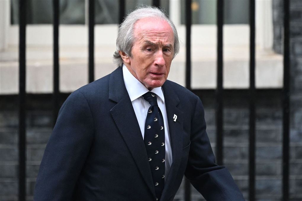 Jackie Stewart går på en gade i jakkesæt.