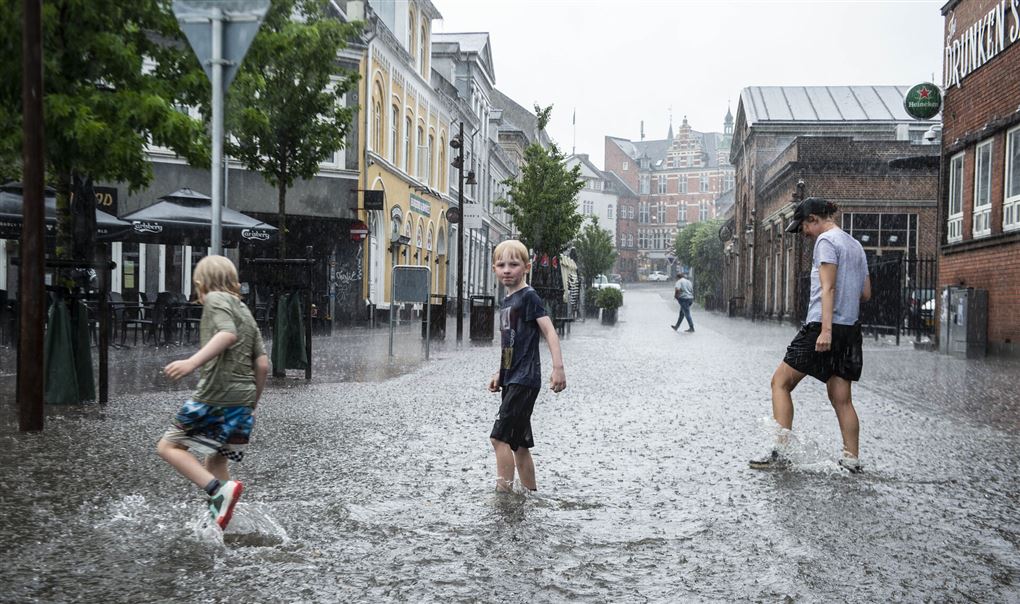 tre personer går i regn til over anklerne