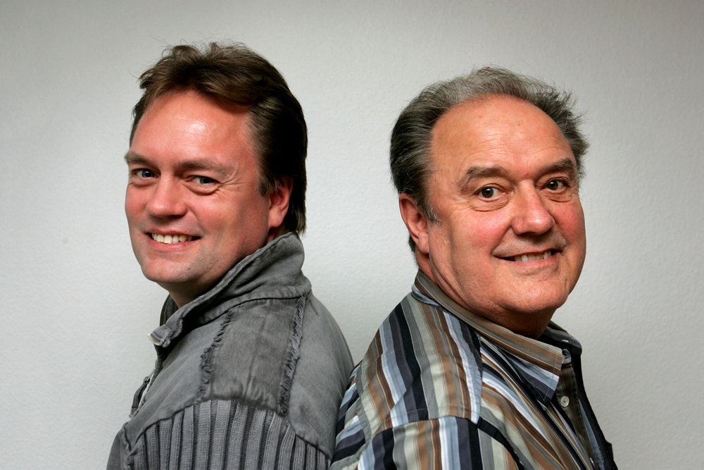 Johnny Hansen og Bjørn med ryggen til hinanden de smiler til kameraet