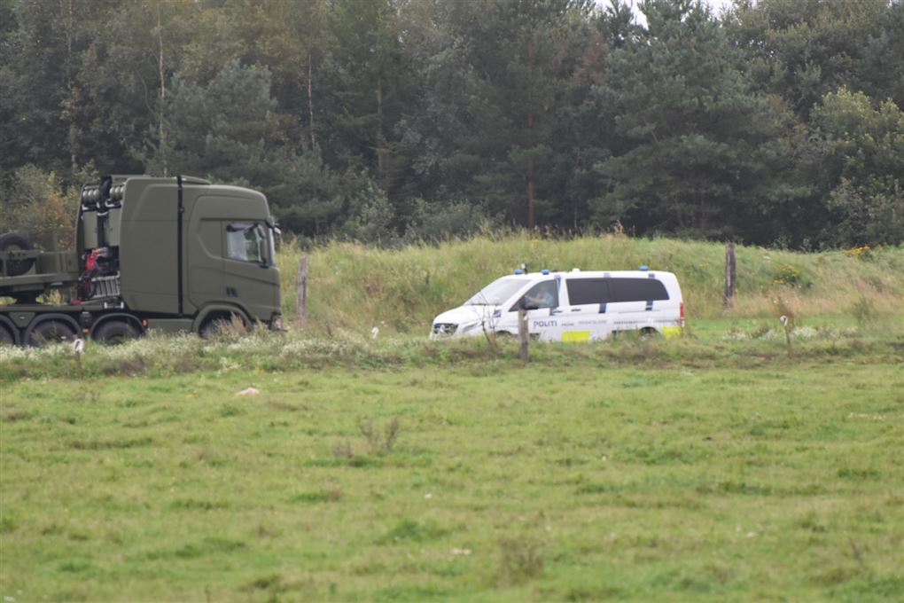 En politibil og en militær lastbil på en eng
