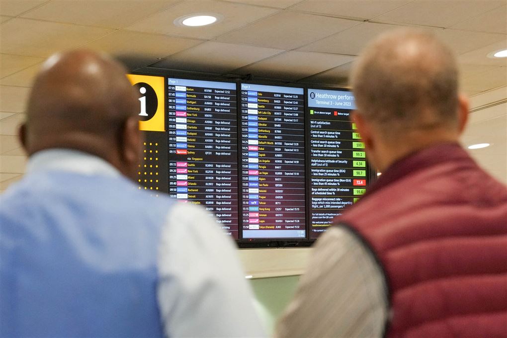 to mænd står og kigger på afgangstavle i lufthavn
