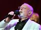 Roger Whittaker synger i en mikrofon i hvid blazerjakke.