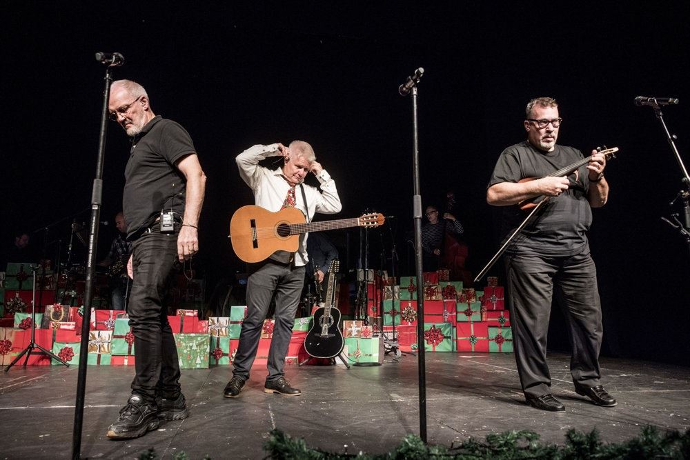 en mand spiller guitar på scenen med andre